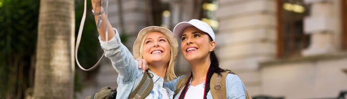 Two women travellers taking selfie before an old house